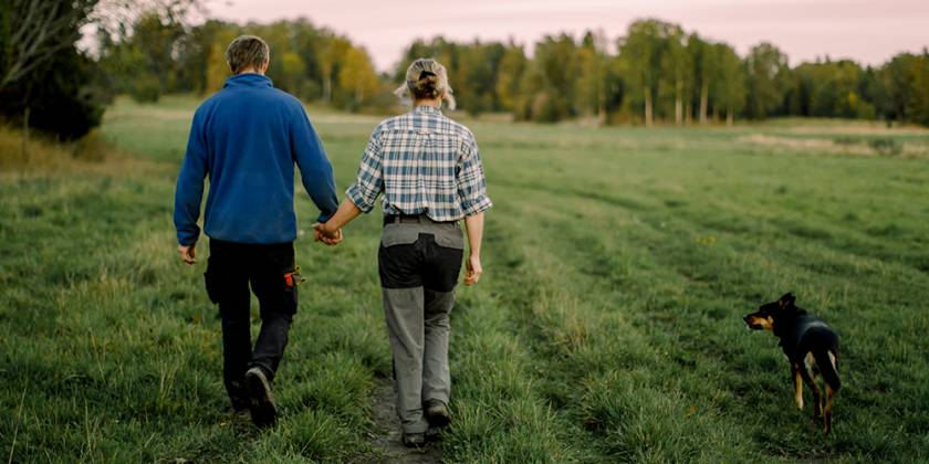 Man, woman and dog walking in field