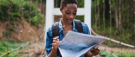 Woman in rural surroundings looking at travel map on bridge