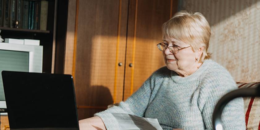 Older woman at home using laptop seated at table