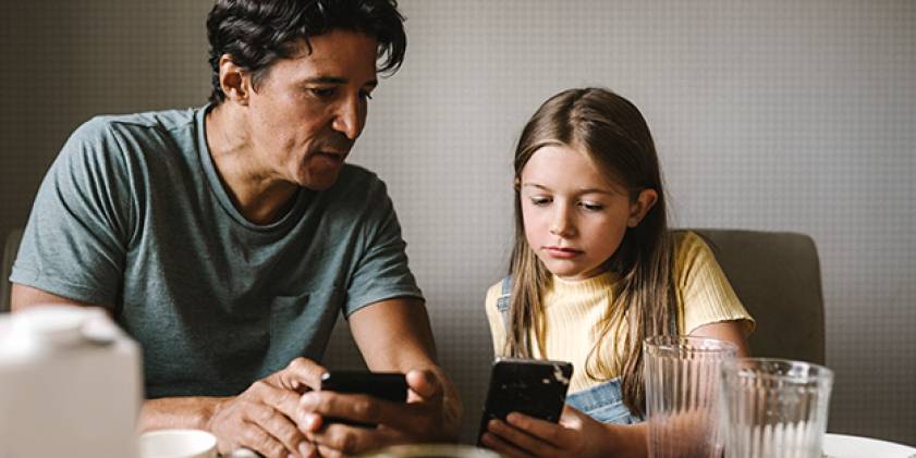Man and young girl looking at mobile phones