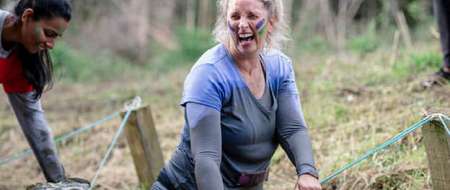 Laughing woman covered in mud taking part in woodland activity